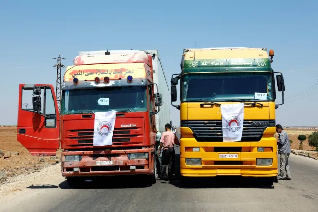 ​ سيارات تحمل مساعدات أثناء توجهها إلى السويداء عبر بصرى الشام في درعا الاثنين (رويترز)