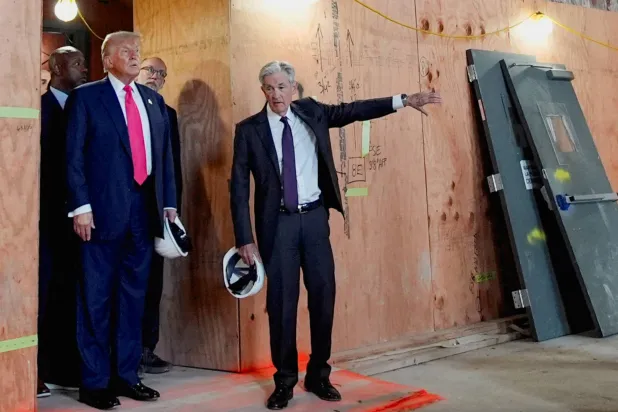 رئيس الاحتياطي الفيدرالي جيروم باول يلوّح بيده بينما ينظر إليه الرئيس الأميركي دونالد ترمب خلال جولة في مبنى الاحتياطي الفيدرالي (رويترز)