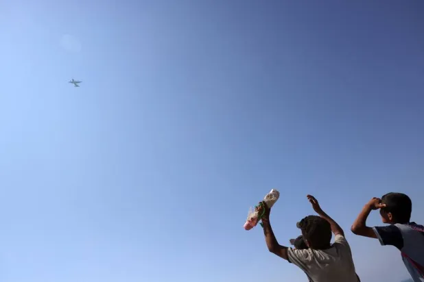Children and youths gather as a C-130 Hercules military transport aircraft flies over during an aid-drop on the northern Gaza Strip on July 27, 2025. (AFP)