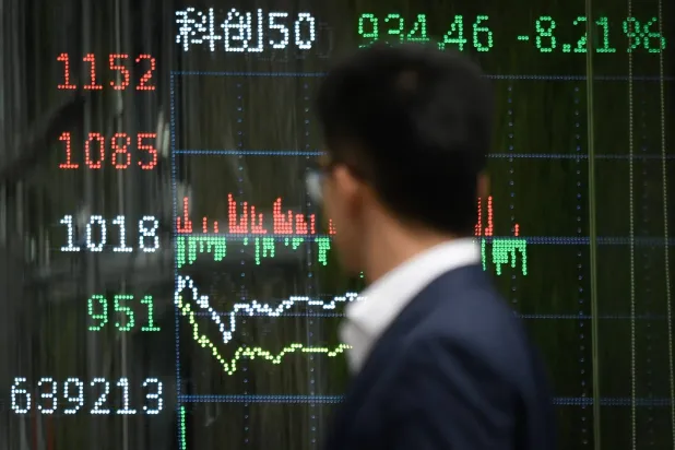 رجل يمر أمام شاشة تعرض تحركات سوق الأسهم الصينية ببكين (أ.ف.ب)