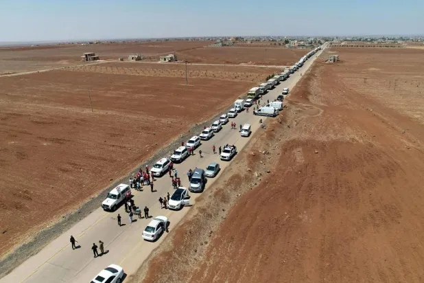 This handout picture released by the official Syrian Arab News Agency (SANA) on July 28, 2025 shows Syrian Red Crescent trucks carrying humanitarian aid arriving at Busra al-Sham in Syria's southern Daraa province before crossing the buffer zone into Sweida province. (SANA / AFP) 