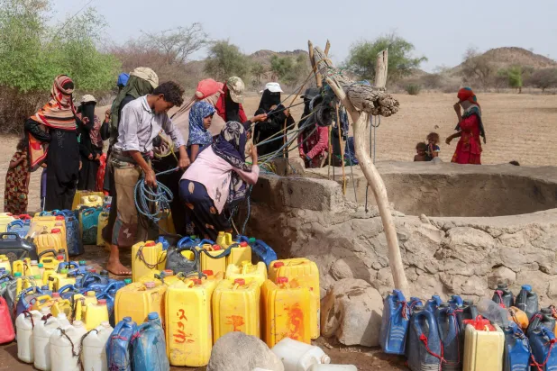 People displaced by conflict gather to top up their jerrycans with water drawn from a well at a makeshift camp in Hays, south of Hodeida in eastern Yemen on July 19, 2025. (Photo by Khaled ZIAD / AFP)