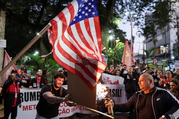 رجل يحرق العلم الأميركي خلال احتجاج على الرسوم الجمركية على المنتجات البرازيلية التي فرضها ترمب في ساو خوسيه دوس كامبوس (رويترز)