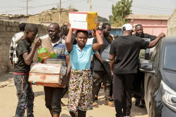 يحضر السكان الطعام إلى منزل سيلفيا موبيالا في حي فيانا - كاووب بي في لواندا في 31 يوليو 2025 والتي يُزعم أنها قُتلت بالرصاص في 30 يوليو 2025 على يد الشرطة الأنغولية (أ.ف.ب)