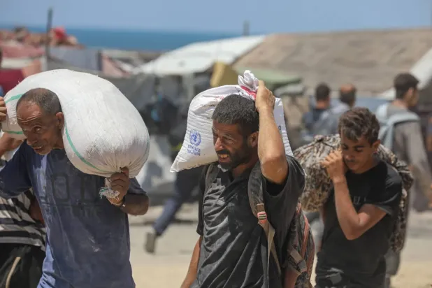 Filistinliler, kuşatma altındaki Gazze Şeridi'ne ulaşan gıda yardımı kapsamında aldıkları un çuvallarını taşıyor (DPA)