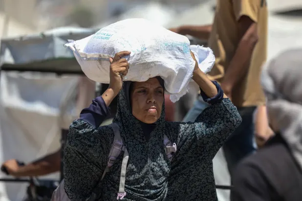 Filistinli bir kadın, Cibaliye'de yıkılmış yolda gıda yardımı taşıyor (DPA)