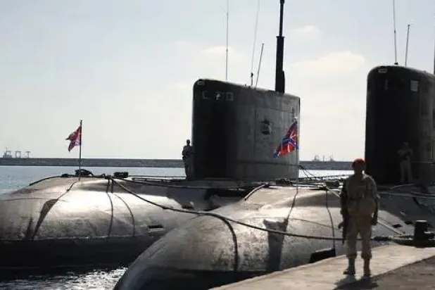 جندي روسي يقف إلى جانب غواصات في قاعدة بحرية روسية (أ.ف.ب)
