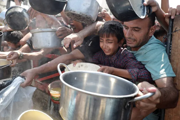 فلسطينيون يكافحون للحصول على الغذاء من مطبخ خيري في مدينة غزة (رويترز)