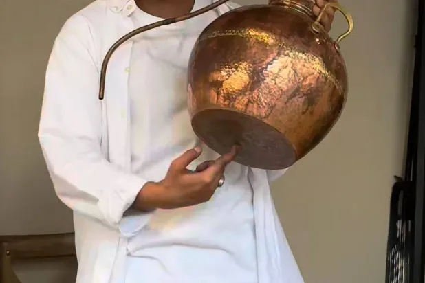 عزام آل حمدان يشرح عملياً تقطير الزهور في إحدى ورش العمل التي يقدمها في معمله بجدة التاريخية (الشرق الأوسط)