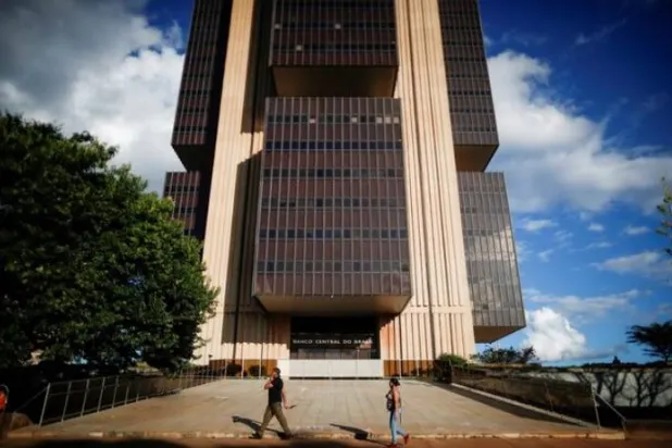 أشخاص يسيرون أمام مبنى المقر الرئيسي للبنك المركزي في برازيليا (رويترز)
