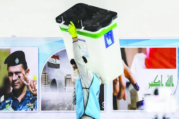 موظف في مفوضية الانتخابات العراقية يحمل صندوقاً لفرز الأصوات في ديسمبر 2023 (أ.ف.ب)