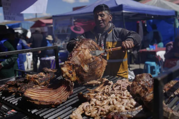 بائع يشوي اللحم خلال أحد المعارض في بوليفيا (أ.ب)