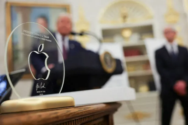 ترمب يتحدث بينما يقدم كوك إعلان «أبل» عن استثمار بقيمة 100 مليار دولار في التصنيع الأميركي وإلى جانبه الهدية المصنوعة من الذهب (رويترز)