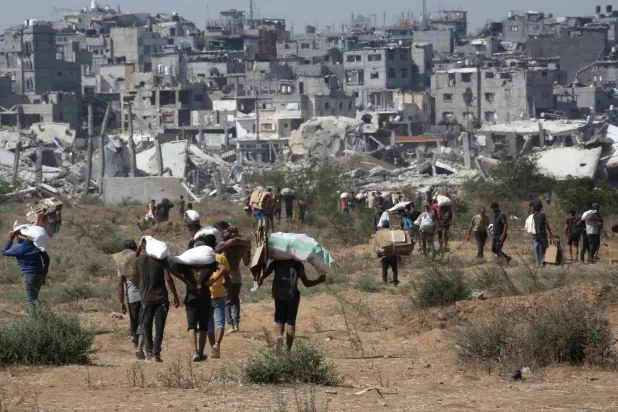 نازحون فلسطينيون في مخيم النصيرات للاجئين يحملون طروداً غذائية ومواد أخرى تمكنوا من الحصول عليها من نقطة توزيع مساعدات في «ممر نتساريم» في وسط قطاع غزة (أ.ف.ب)