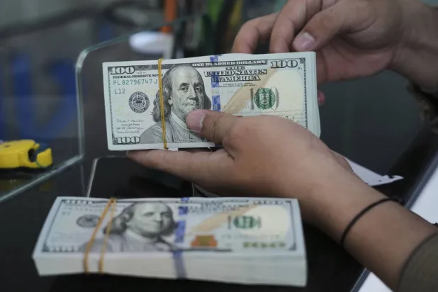 موظف يعدّ أوراق الدولار الأميركي في مكتب صرافة بجاكرتا، إندونيسيا (رويترز)