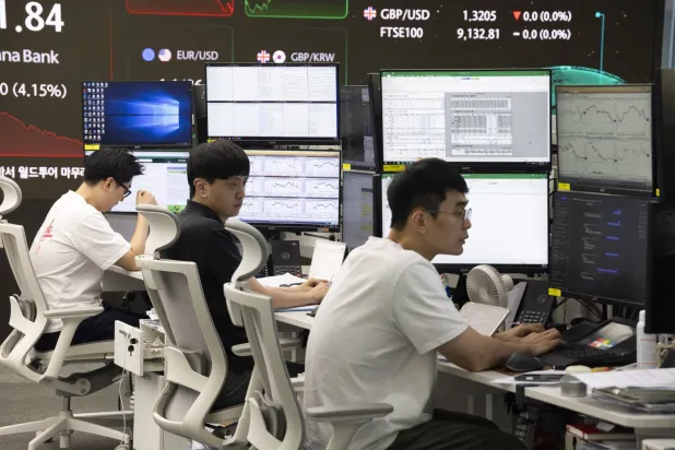 متداولون يعملون أمام شاشات مراقبة في بنك هانا في سيول (إ.ب.أ)