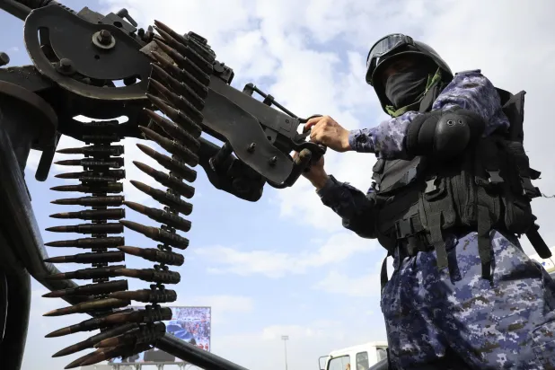 عنصر حوثي يمسك رشاشاً ثقيلاً على متن عربة أمنية (إ.ب.أ)