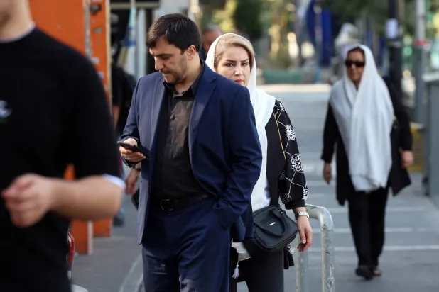 إيرانيون يسيرون في أحد شوارع طهران (إ.ب.أ)