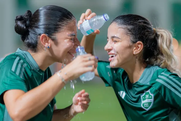 لاعبتان من الأهلي تسكبان الماء على وجهيهما بعد نهاية التدريبات (موقع النادي)