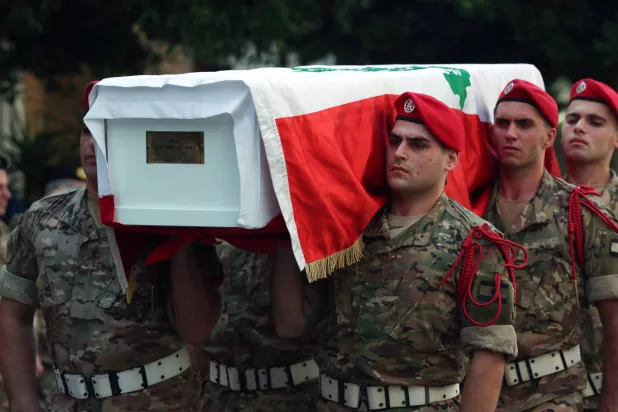 عناصر من الجيش يحملون زميلاً لهم قتل أثناء الكشف على منشأة لـ«حزب الله» في الجنوب (إ.ب.أ)