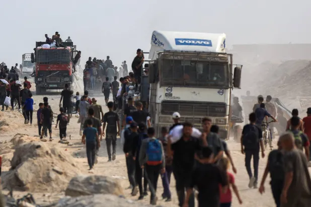 فلسطينيون يسعون للحصول على المساعدات من الشاحنات في بيت لاهيا بشمال قطاع غزة (رويترز)