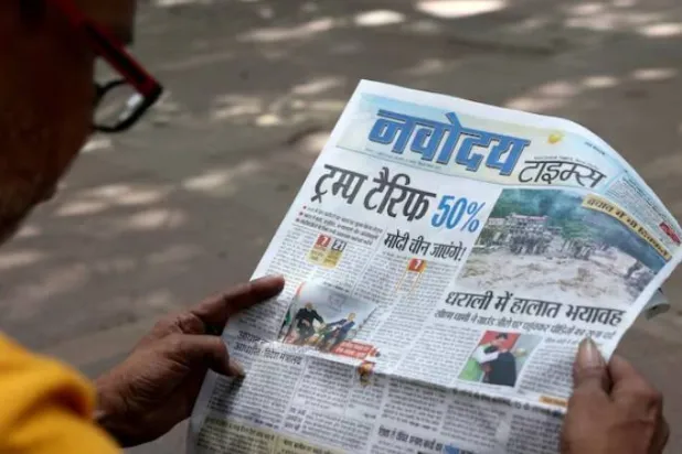 رجل يقرأ تقارير عن رسوم دونالد ترمب الإضافية على البضائع الهندية في نيودلهي (رويترز)
