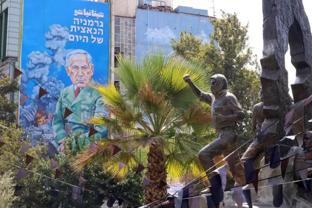 لوحة دعائية مكتوب عليها بالفارسية كلمة «هتيانياهو» وبالعبرية عبارة «النازي الألماني لليوم» معلقة فوق مركز التنسيق الإيراني - الفلسطيني وسط طهران (أ.ف.ب)