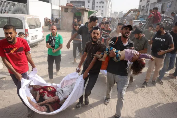 فلسطينيون ينقلون جثث أطفال قُتلوا في غارة إسرائيلية على حي الزيتون إلى مستشفى الشفاء بمدينة غزة (أ.ف.ب)
