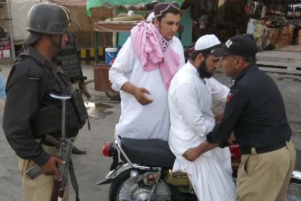 مسؤولون أمنيون باكستانيون يفتشون رجلاً عند نقطة تفتيش في كويتا عاصمة إقليم بلوشستان المضطرب 8 أغسطس (إ.ب.أ)