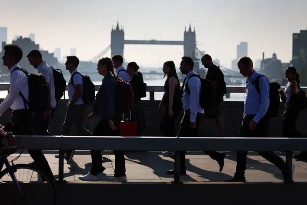 أشخاص يعبرون جسر لندن في طريقهم إلى العمل بلندن (إ.ب.أ)