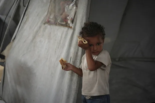 طفل فلسطيني يمسح العرق عن جبينه جراء الحرارة في خيمة عائلته بمدينة غزة الثلاثاء (أ.ب)