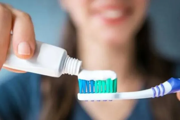 امرأة تضع معجون الأسنان على فرشاة قبل تنظيف أسنانها (أ.ف.ب)