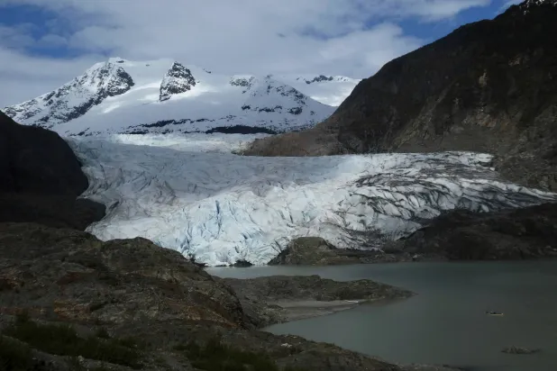 FILE - A canoe, bottom right, glides on Mendenhall Lake, in front of the Mendenhall Glacier, on Sunday, May 18, 2025, in Juneau, Alaska. (AP Photo/Becky Bohrer, File)