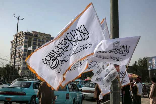 أفغانيات يسرن أمام أعلام «طالبان» في كابل عشية الذكرى الرابعة لاستيلاء الحركة على السلطة وسقوط الحكومة الأميركية عام 2021 الخميس 14 أغسطس 2025 (أ.ف.ب)