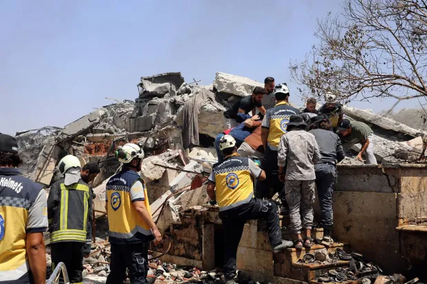 فرق الإنقاذ تخلي الضحايا من وسط الأنقاض بعد انفجار هز إدلب يوم 14 أغسطس 2025 (أ.ف.ب)