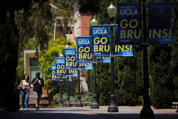 أشخاص يسيرون عبر حرم جامعة كاليفورنيا في لوس أنجليس (رويترز)