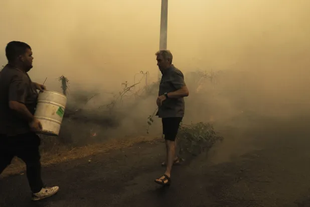 رجل يشاهد عملية إخماد الحرائق في منطقة غاليسيا شمال غربي إسبانيا (إ.ب.أ)