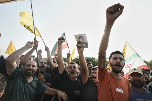 مناصرون لـ«حزب الله» يرفعون قبضاتهم خلال استقبال لاريجاني قرب مطار بيروت الأربعاء (أ.ب)