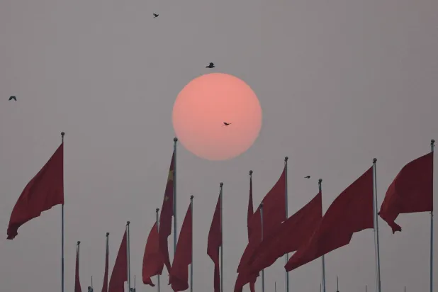 الشمس تشرق بالقرب من العلم الوطني الصيني في يوم الجلسة الختامية للمؤتمر الاستشاري السياسي للشعب الصيني (أرشيفية - رويترز)