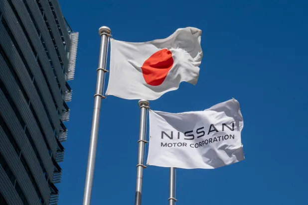 The Japanese national flag and Nissan Motor Corporation's flag fly at the entrance of the company's global headquarters in Yokohama, Kanagawa Prefecture on July 30, 2025. (Photo by Kazuhiro NOGI / AFP)