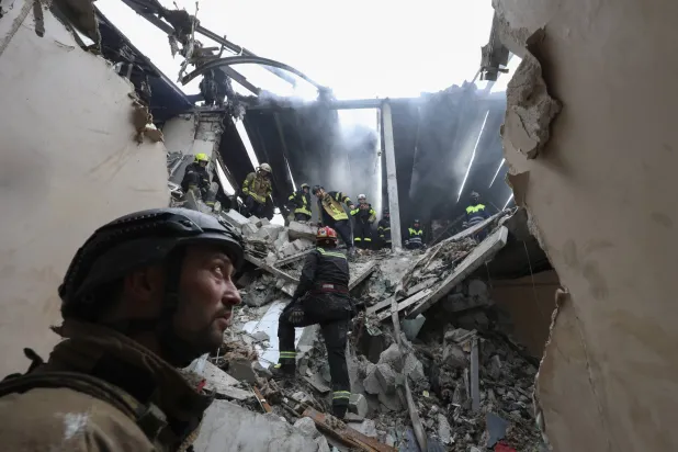 رجال إنقاذ أوكرانيون يعملون في موقع غارة جوية بطائرة مسيّرة على منطقة سكنية في خاركيف شمال شرقي أوكرانيا (إ.ب.أ)
