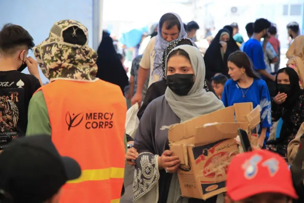 فاطمة رضائي (يمين في الأمام) متطوعة أفغانية توزع إمدادات الإغاثة على المهاجرين الأفغان الواصلين حديثاً والمُرحَّلين من إيران عند معبر «إسلام قلعة» الحدودي بولاية هرات في 24 يوليو 2025 (أ.ف.ب)