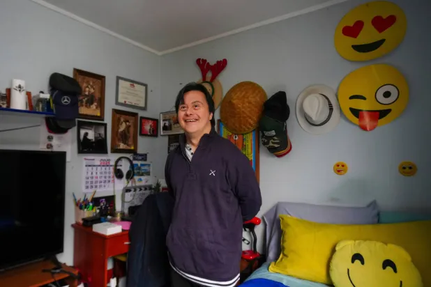 الممثل سيباستيان سولورزا الذي يعاني من «متلازمة داون» ويسعى للترشح للرئاسة مرشحاً مستقلاً يبتسم خلال مقابلة في منزله بسانتياغو (أ.ب)