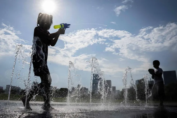 أطفال يلعبون بجوار نوافير مياه في إحدى الحدائق بالعاصمة اليابانية طوكيو (أ.ف.ب)