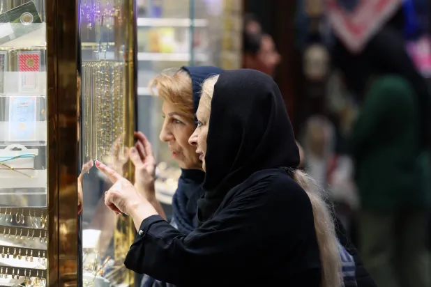نساء إيرانيات ينظرن إلى المجوهرات الذهبية في متجر بسوق تجريش القديم في طهران (إ.ب.أ)
