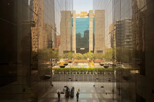 أشخاص يسيرون بين المباني في مركز تجاري في نيودلهي (رويترز)