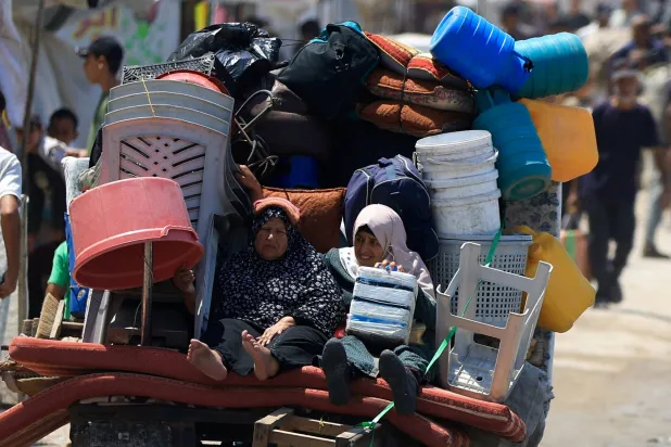 فلسطينيتان مع أغراضهما أثناء النزوح من مدينة غزة صوب الجنوب (رويترز)