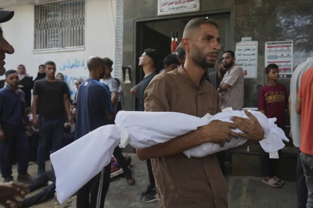 فلسطيني يحمل جثمان طفل قُتل في غارة عسكرية إسرائيلية على قطاع غزة (أ.ب)