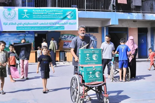 أسر فلسطينية لدى تسلمها سلالاً غذائية قدّمتها السعودية لسكان قطاع غزة (واس)