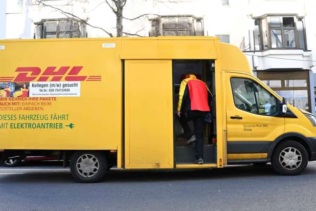 عامل يدخل مركبة تابعة لمجموعة «دي إتش إل» في برلين (رويترز)